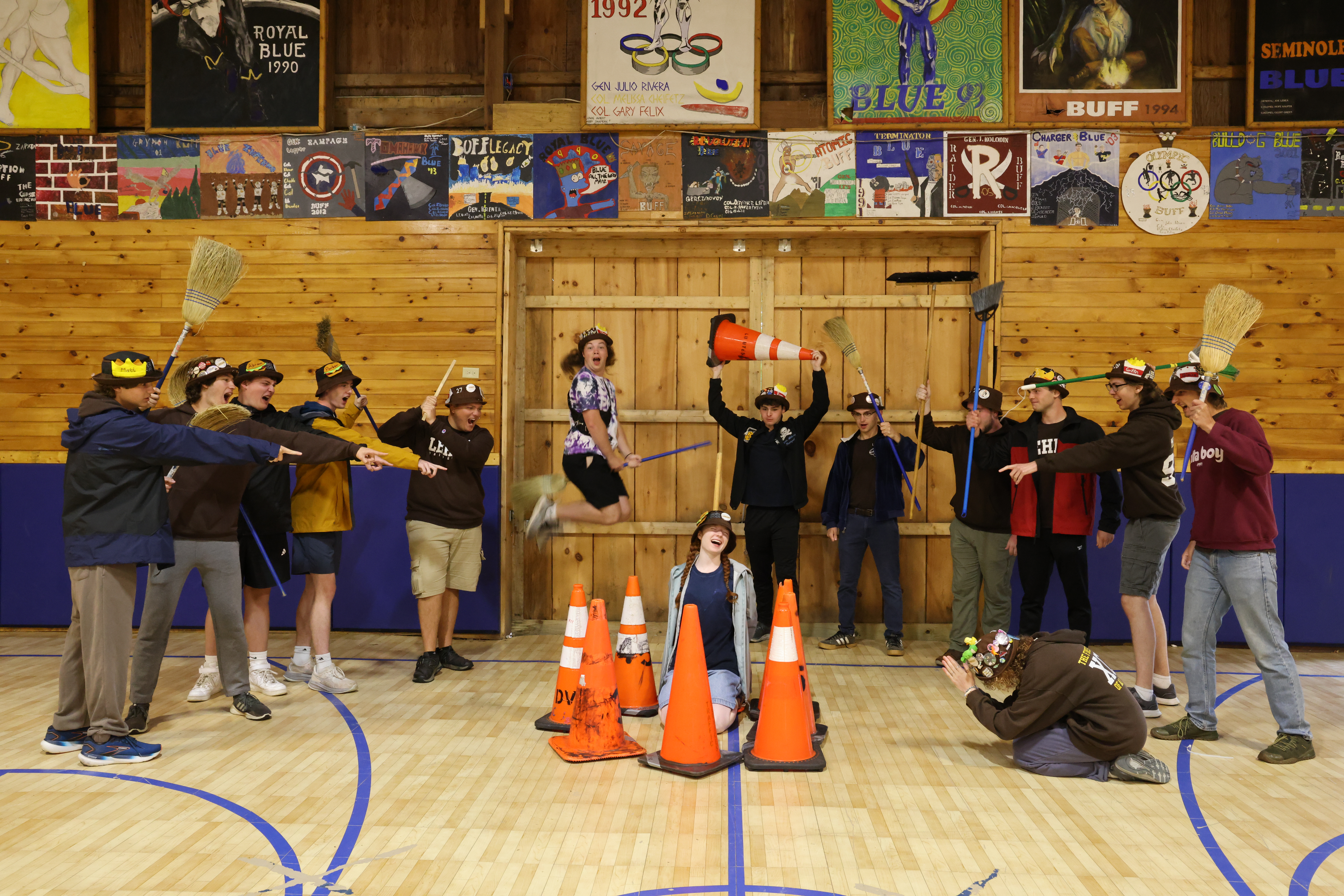Ranks 6 and 9 pretend to burn one of their members at the stake while pointing and holding brooms as weapons.