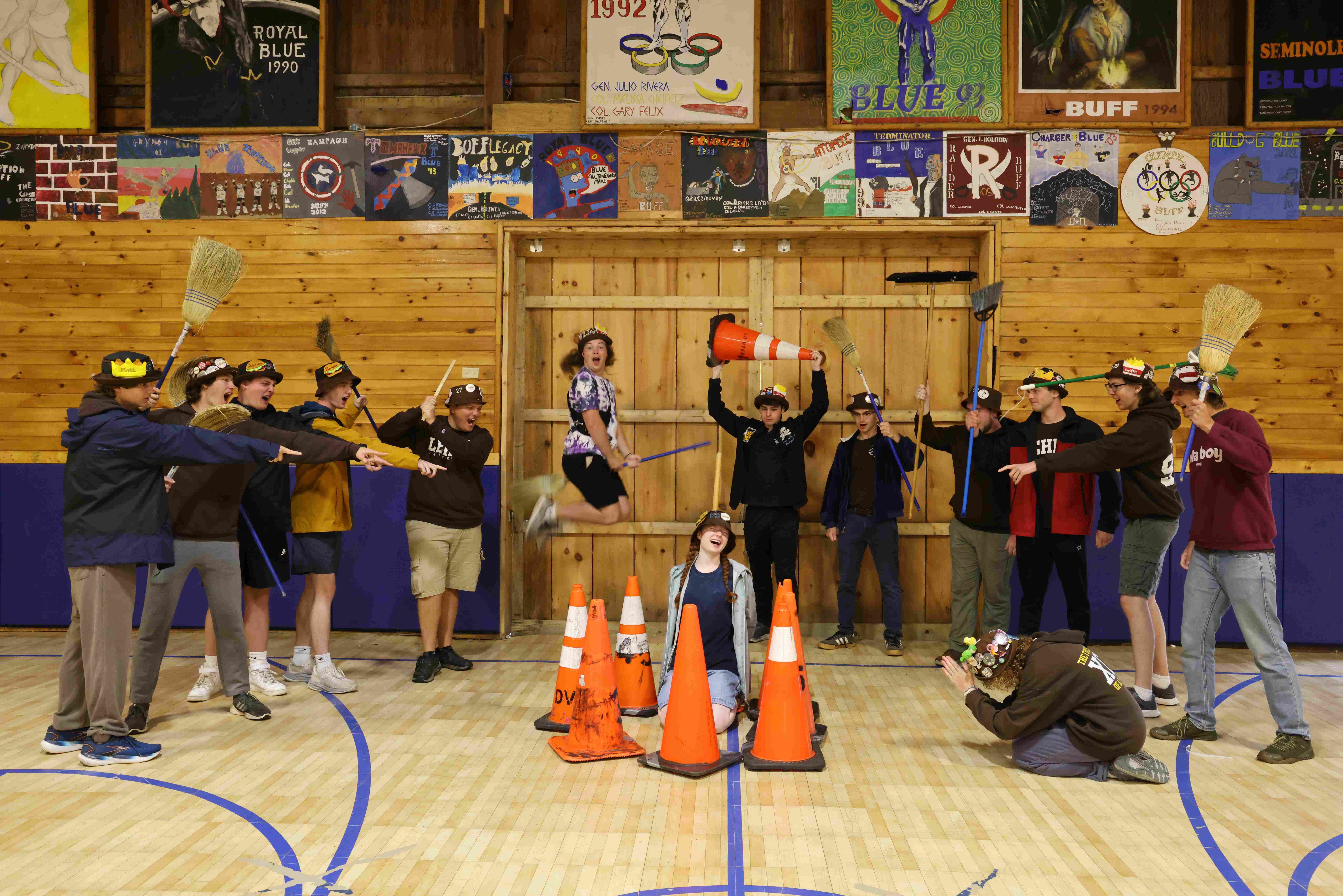 Ranks 6 and 9 pretend to burn one of their members at the stake while pointing and holding brooms as weapons.